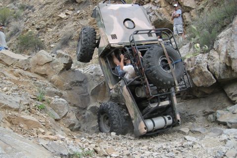 1966 Ford Bronco - Off-road vehicle struggling on a steep, rocky incline, with onlookers observing the situation.