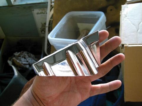 1986 Ford Bronco - A chrome trim piece is held in a hand, with a blurred background of storage containers and boxes.