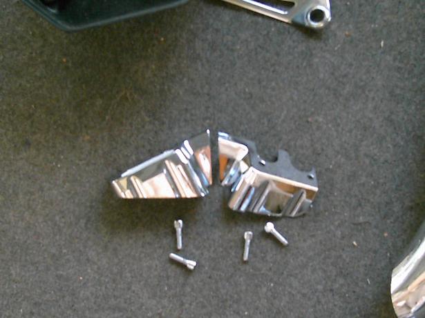 Chrome trim pieces and screws on a dark textured surface