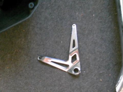 1986 Ford Bronco - A metal bracket with decorative cutouts is shown on a carpeted surface.