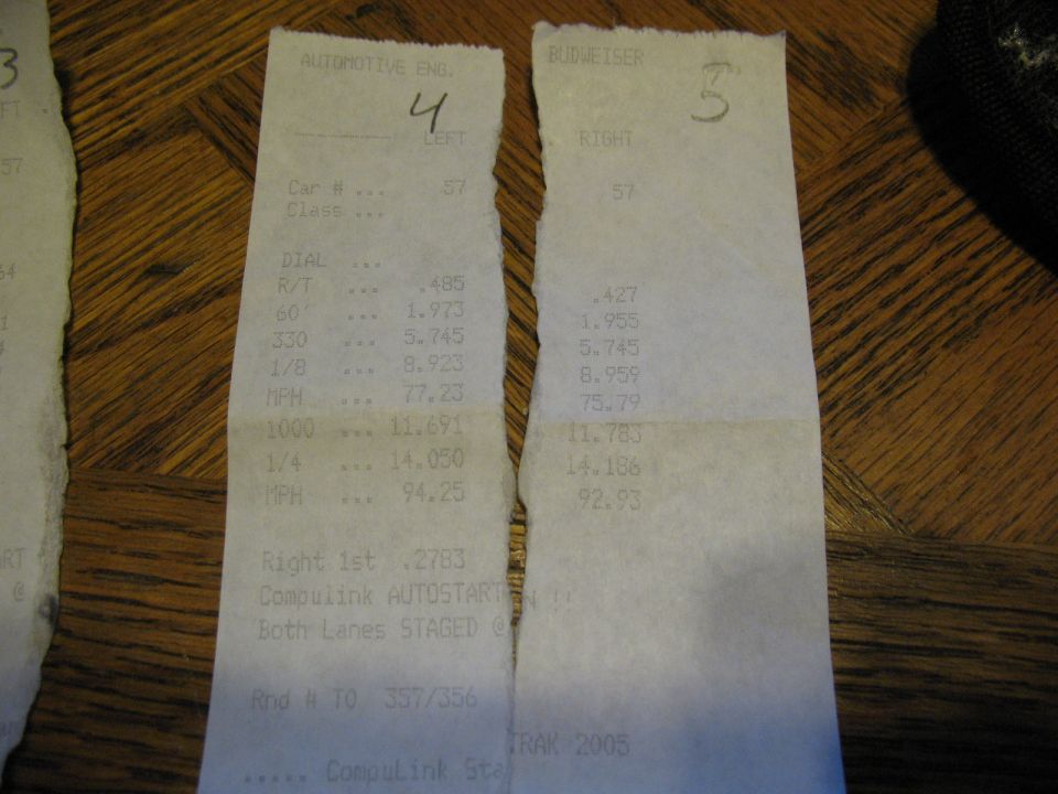 Two drag racing timing slips for Car #57 showing 14.050 and 14.186 quarter-mile times on a wood table