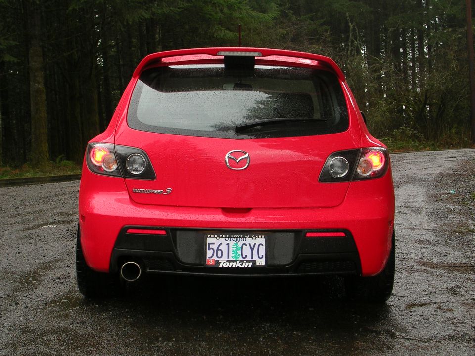 Rear view of wet red Mazdaspeed 3 hatchback with Oregon plate and roof spoiler