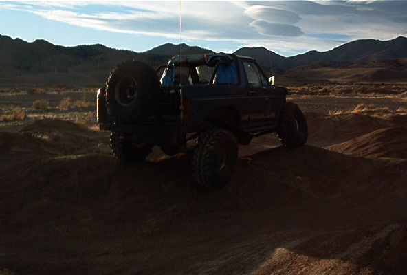 Ford Bronco on a dirt hill with mountains in the background