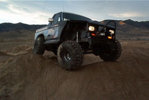 1986 Ford Bronco - This modified Ford Bronco navigates a dirt terrain under a cloudy sky.