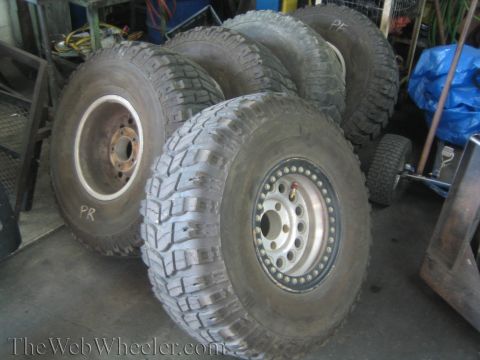 1968 Ford Mustang - Several large off-road tires are stacked and leaning in a workshop setting.