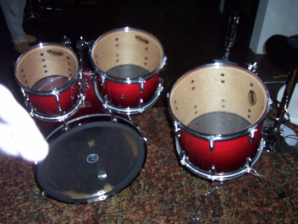 Red drum kit with black mesh head on floor tom, on carpet