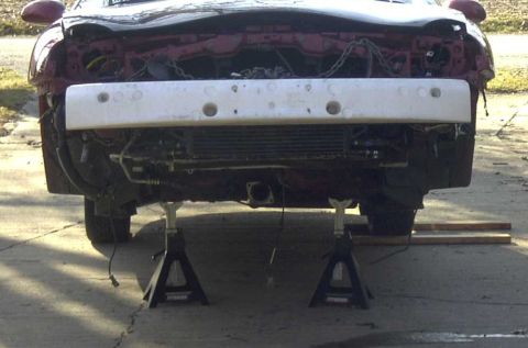 1997 Ford Taurus - Car front end disassembled on jack stands, showing exposed radiator and wiring.
