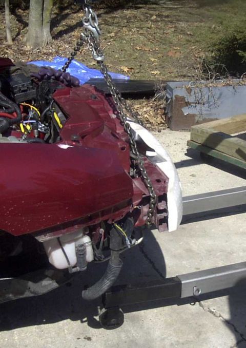 1997 Ford Taurus - A car's front end, partially disassembled and lifted by chains, is the subject of this photograph.