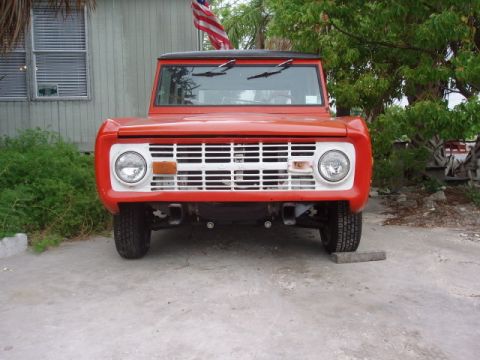 1968 Ford Bronco - Front view of a red 1968 Ford Bronco, parked outdoors with a house and trees in the background.