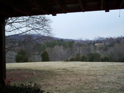 1971 Ford Ranchero - View from under a wooden porch roof across a dormant winter lawn toward bare hardwoods, scattered evergreens and rolling wooded hills under…