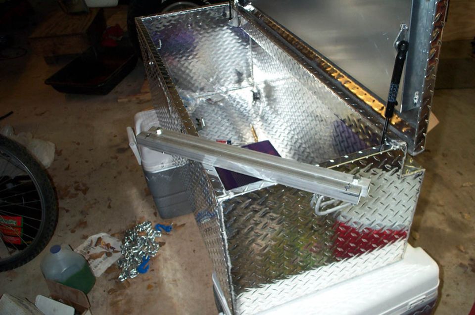 Diamond plate toolbox with open lid and gas strut