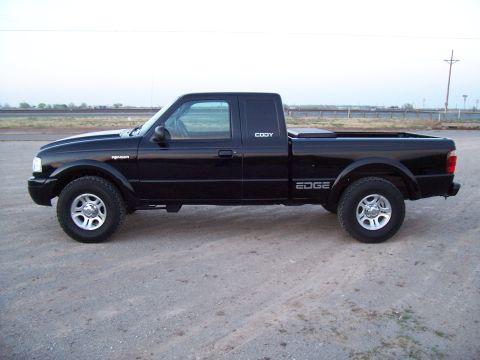 2003 Ford Ranger - A black 2003 Ford Ranger Edge pickup truck is parked on a dirt lot with a fence and utility pole in the background.
