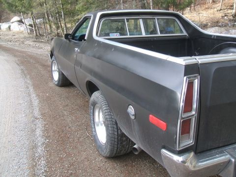 1974 Ford Ranchero - Rear view of a black 1974 Ford Ranchero parked on a dirt road with trees in the background.