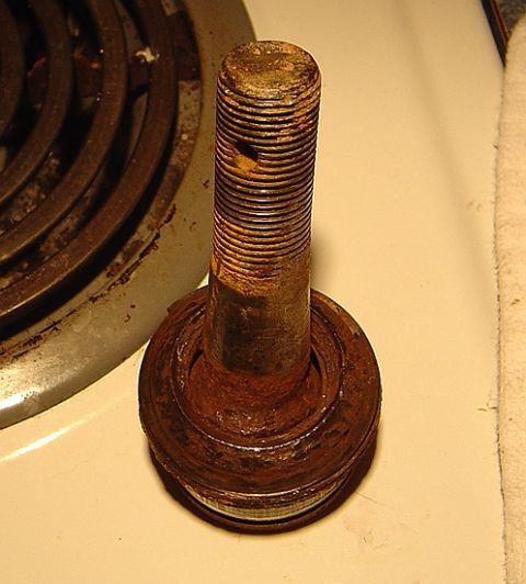 1986 Ford Bronco - A heavily rusted ball joint rests on a stovetop next to a burner element.