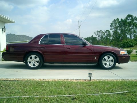 2004 Ford Crown Victoria - Side profile of a maroon 2004 Ford Crown Victoria sedan parked in a driveway.