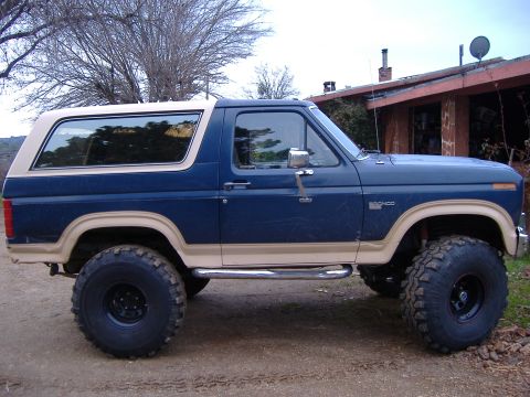 1986 Ford Bronco - Side view of a lifted 1986 Ford Bronco with custom wheels and off-road tires.