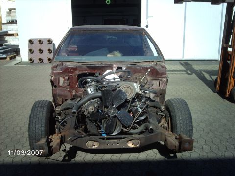 1979 Ford Ranchero - The front end of a vehicle, stripped down to reveal the engine and chassis, sits outdoors.