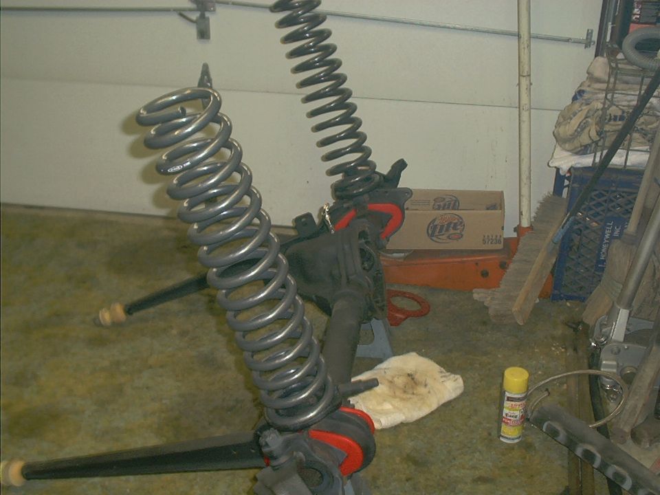 Two large coil springs and suspension components on jack stands