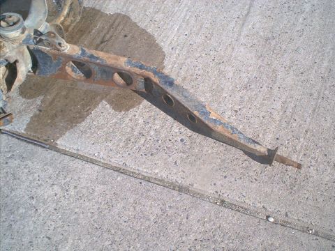 1986 Ford Bronco - Close-up of a weathered vehicle suspension component resting on a concrete surface.