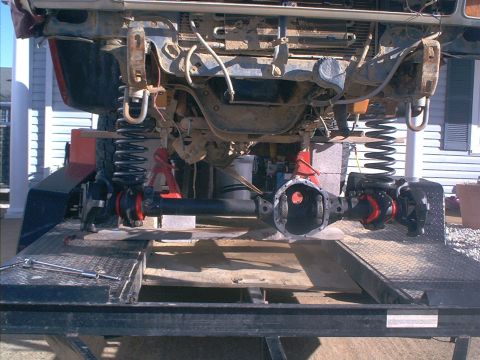 1986 Ford Bronco - Front axle assembly and suspension parts are visible, mounted on a trailer for work.