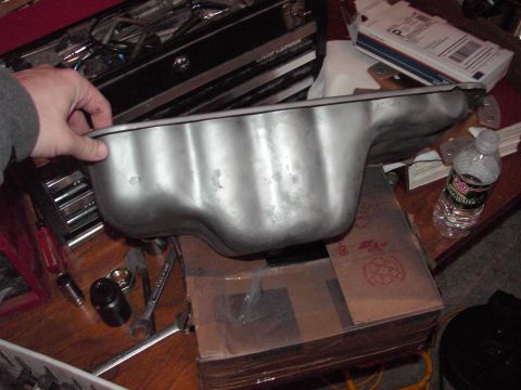 1989 Ford Probe - A metal oil pan is shown in a workshop setting with tools and boxes nearby.