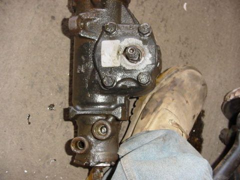1992 Ford Bronco - A close-up view of a steering gear box, with a person's foot wearing a tan boot visible.