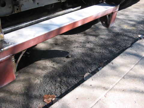 1991 Ford Bronco - The underside of a vehicle, showing the frame and a red bumper, is parked on asphalt.