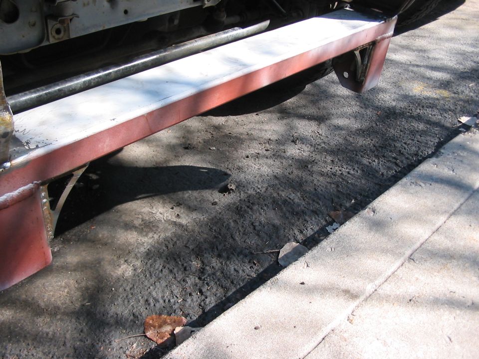 close-up of vehicle frame and red bumper with metal supports underneath