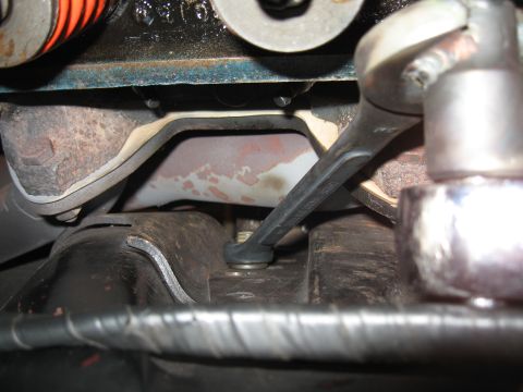 1968 Shelby GT500 - Close-up of a mechanic's hand using a wrench on a vehicle's suspension system.