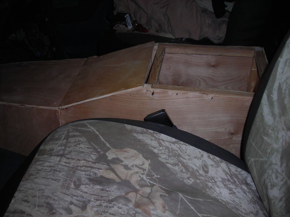 Custom wooden console box in vehicle interior with camouflage seat cover