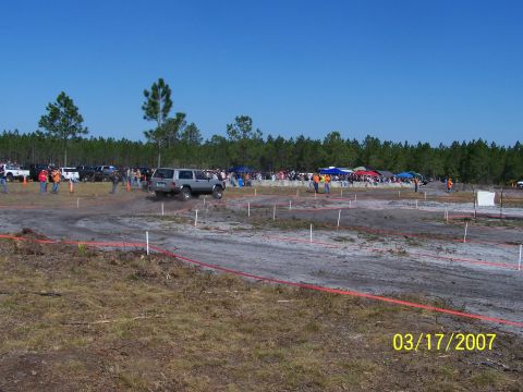 1989 Ford Bronco - Off-road event with spectators and vehicles on a dirt course under a clear blue sky.