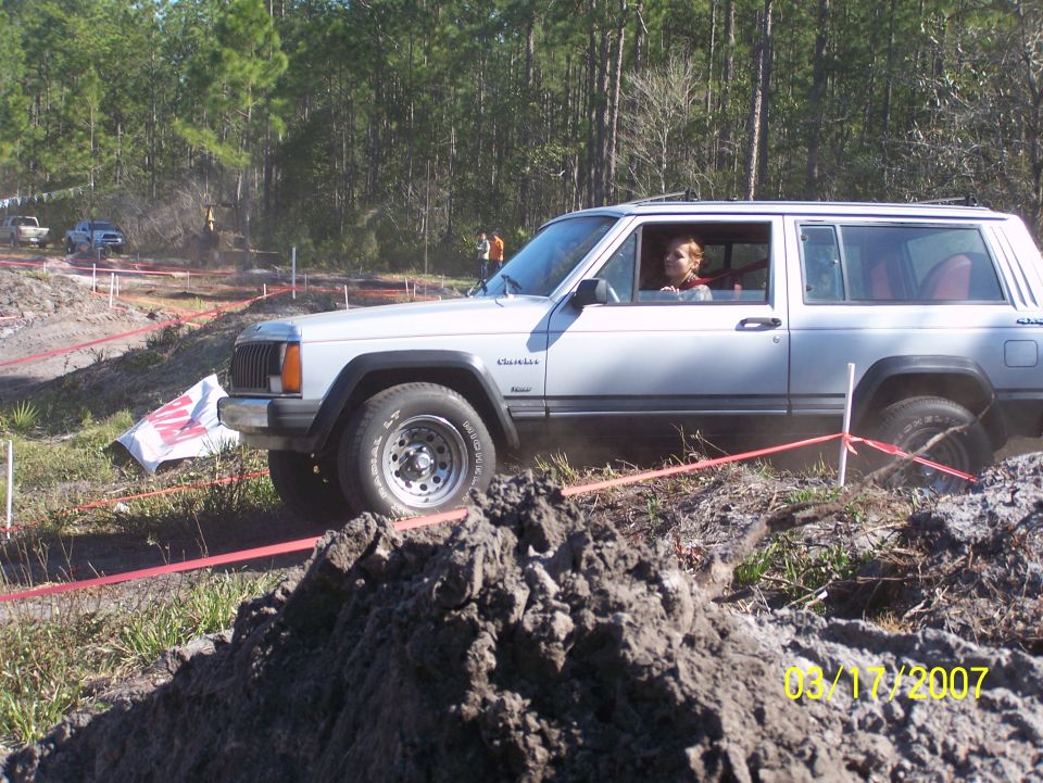 White Jeep Cherokee XJ driving on an off-road course with a person inside
