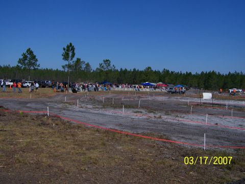 1989 Ford Bronco - An outdoor event with many people and vehicles gathered on a dirt track.