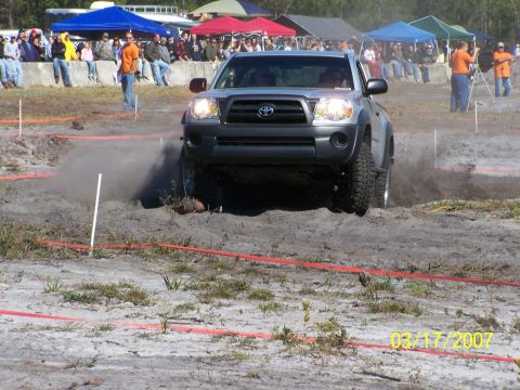 1989 Ford Bronco - A Toyota Tacoma navigates an off-road obstacle course with spectators watching.