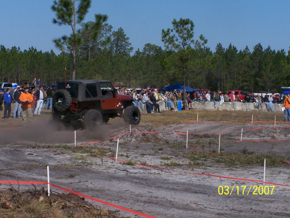 Red Jeep Wrangler kicking up dust on an off-road course