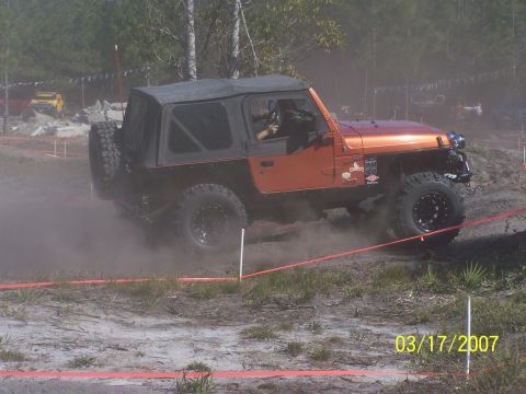 1989 Ford Bronco - A Jeep Wrangler navigates a dusty off-road course with orange and white markers.