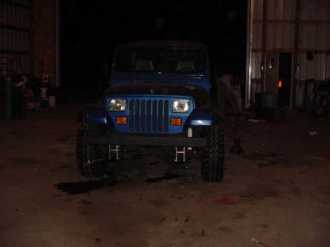 1992 Ford Bronco - Front view of a blue Jeep Wrangler, likely from the early 1990s, parked in a garage.