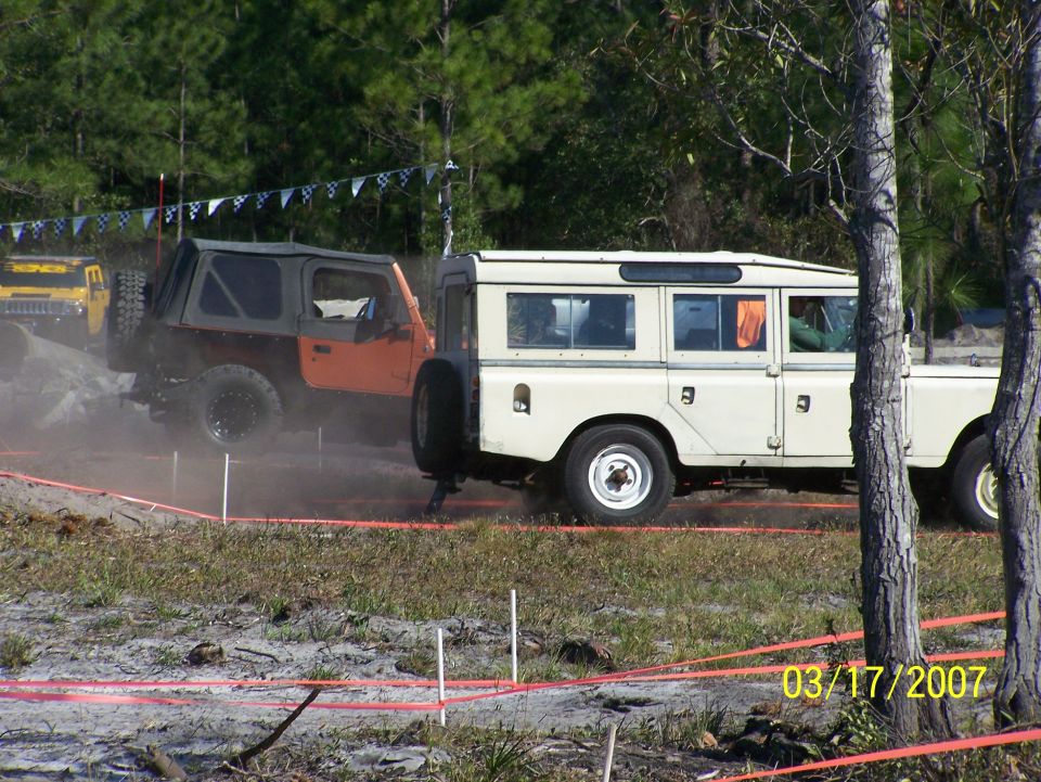 Cream Land Rover Series III and orange Jeep Wrangler in off-road event