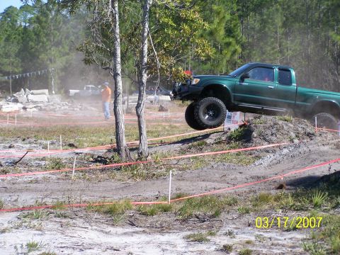 1989 Ford Bronco - Off-road event with a green pickup truck navigating a dirt obstacle course.