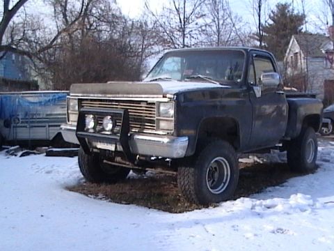 1990 Ford Bronco - This black pickup truck features a prominent bull bar with auxiliary fog lights, suggesting it's equipped for off-road use.