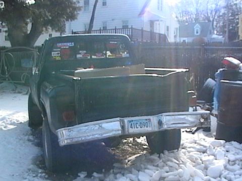 1990 Ford Bronco - Rear view of a green pickup truck with a license plate and stickers on the back window.