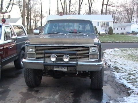1990 Ford Bronco - A truck with a grille and bumper-mounted lights is parked next to another vehicle.
