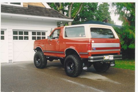 1987 Ford Bronco - This 1987 Ford Bronco is parked in front of a residential garage, showing its lifted suspension and two-tone paint scheme.