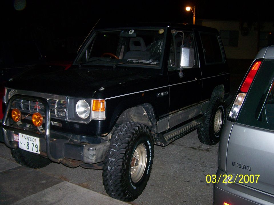Black two-door Pajero SUV at night with brush bar, amber fog lights, and BFGoodrich mud tires