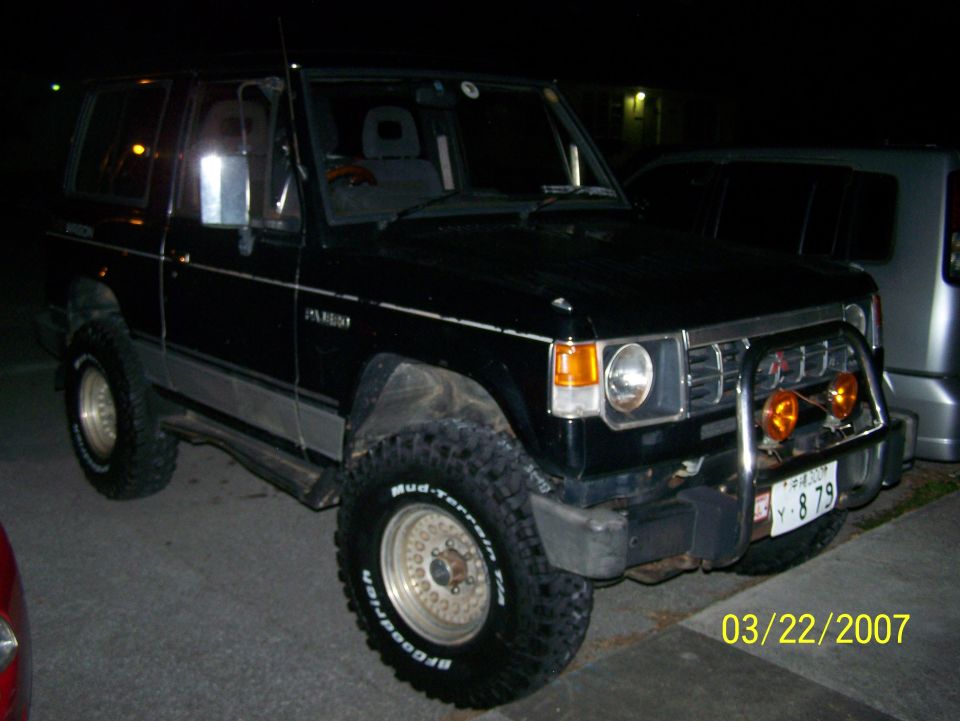 Black 2-door Mitsubishi Pajero SUV at night with bull bar, amber lights, and BFG Mud-Terrain tires