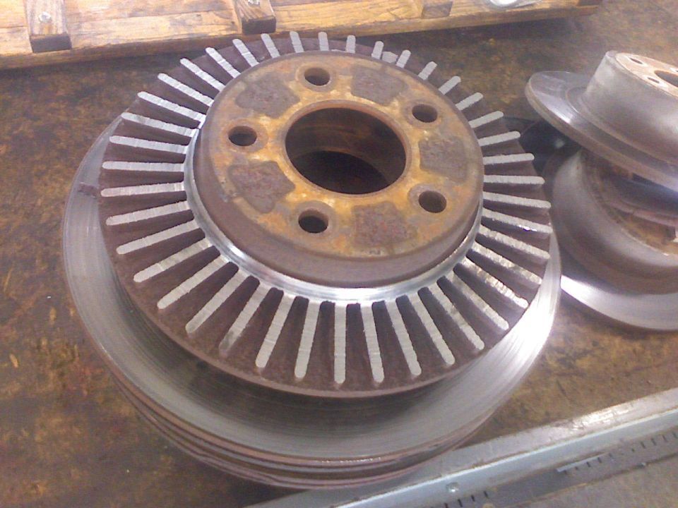 Stack of rusty brake rotors, one with cooling fins