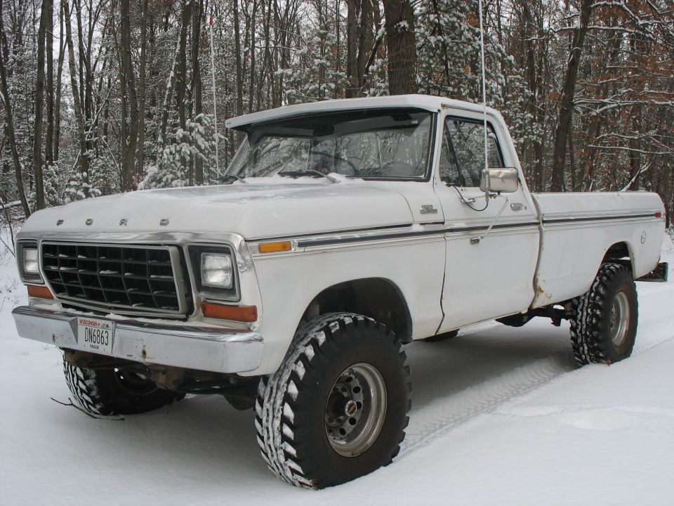 White 1979 Ford F-250 pickup truck with large tires in snowy woods