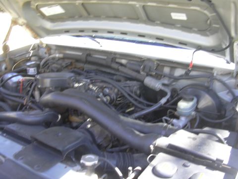 1992 Ford F-250 - The engine bay of a truck is shown with various hoses, wires, and components visible under the hood.