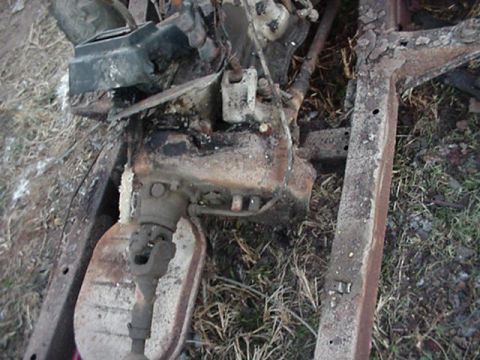 1992 Ford Bronco - Close-up view of heavily rusted vehicle chassis and engine parts, suggesting significant age or damage.