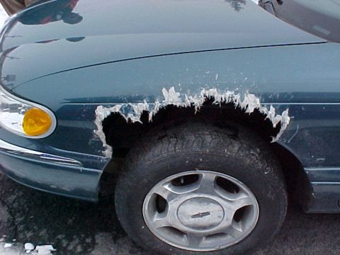 1978 Ford Mustang II - A car's front fender shows significant damage from ice accumulation around the wheel well.